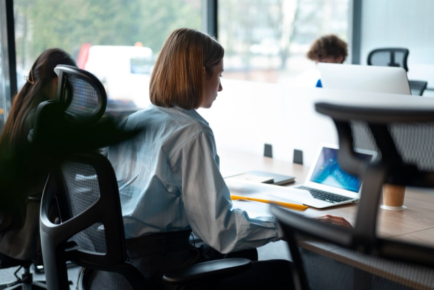 Une femme travail dans un espace de coworking ouvert, assise devant son pc portable sur son bureau