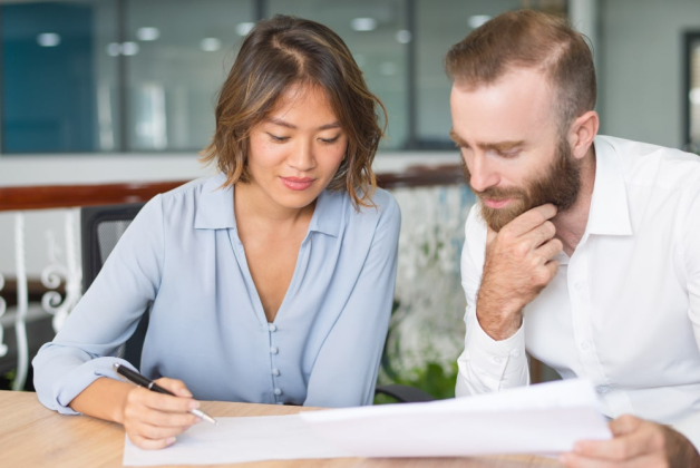 Un homme et une femme assis à une table sont en tain d'élaborer un document ensemble