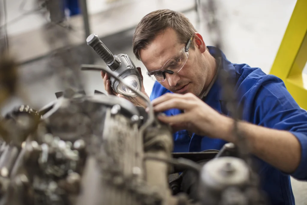 Un méchanicien automobile est en train de travailler sur un moteur de voiture dans son garage