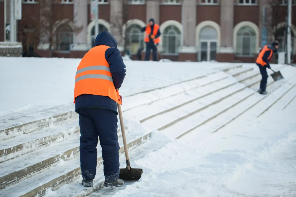 Des ouvriers en tenue haute-visibilité sont en train de déneiger avec des pelles