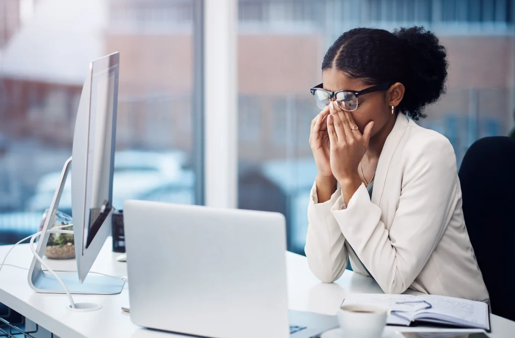 Une femme à son bureau est en train de se tenir la t^te de fatigue